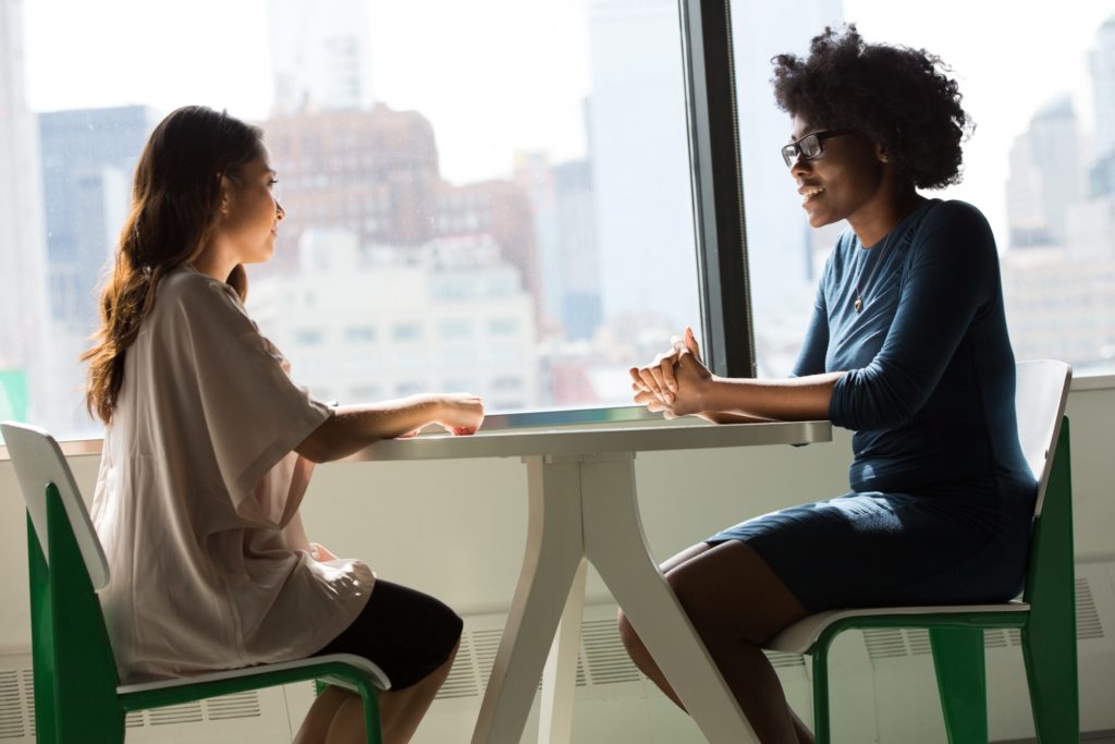 Two people meeting at table with view of city.