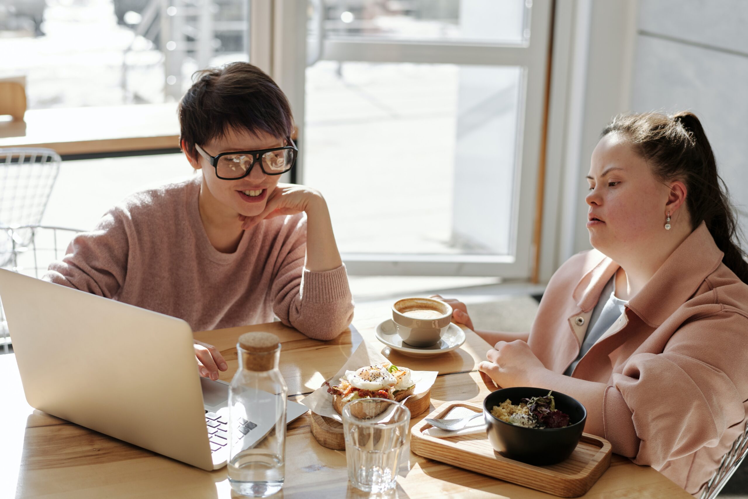 Two people eating looking at laptop.