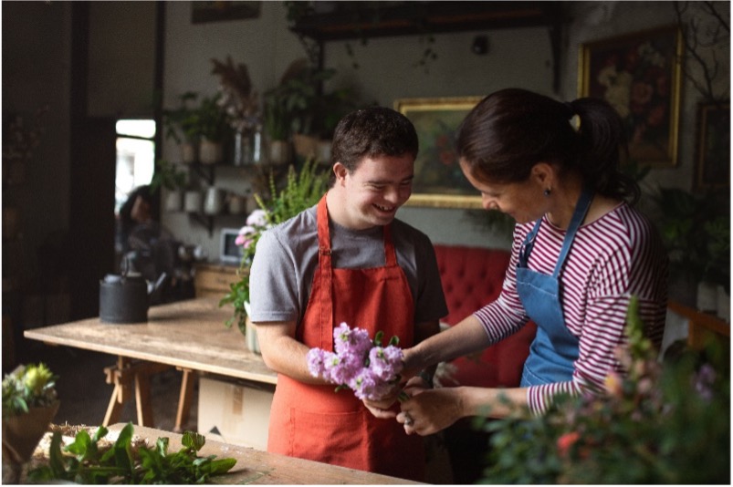 Man and woman holding purple flower in flower shop.