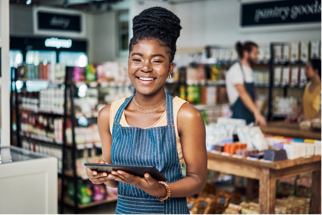 Woman smiling holding tablet in grocery store.