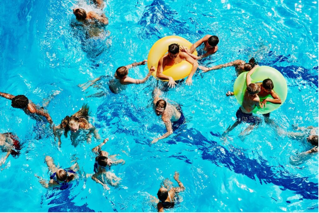Large group of youth swimming in public pool.