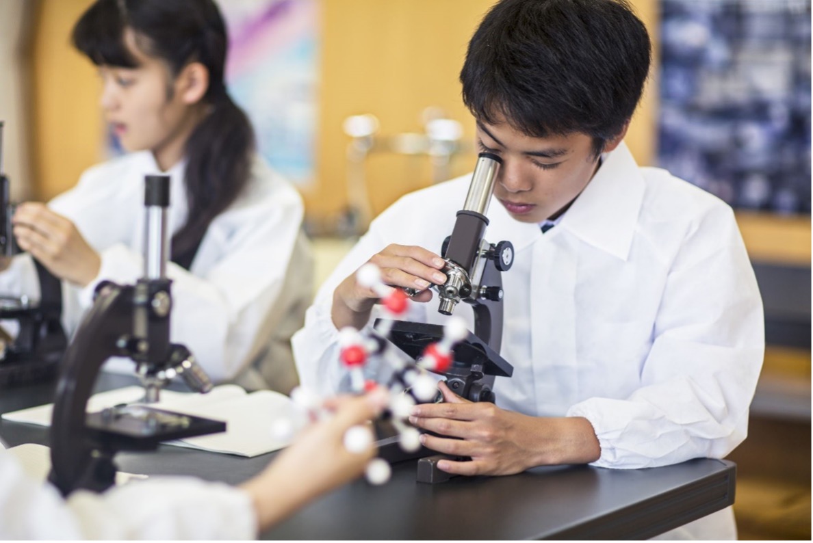 Man in lab coat looking into microscope.