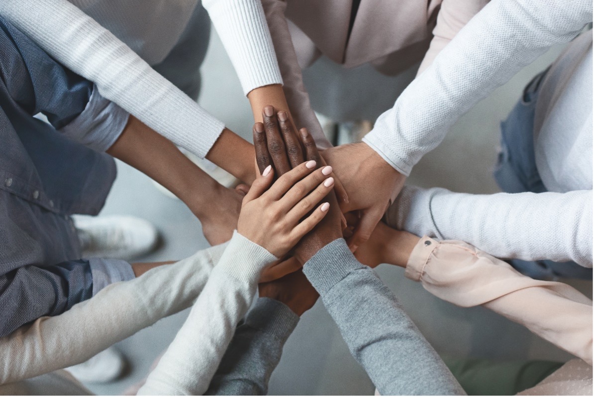 Multiple people in a circle with hands on top of each other.